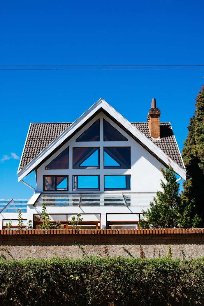 our-story A modern A-frame house with large windows against a clear blue sky, showcasing contemporary architecture.
