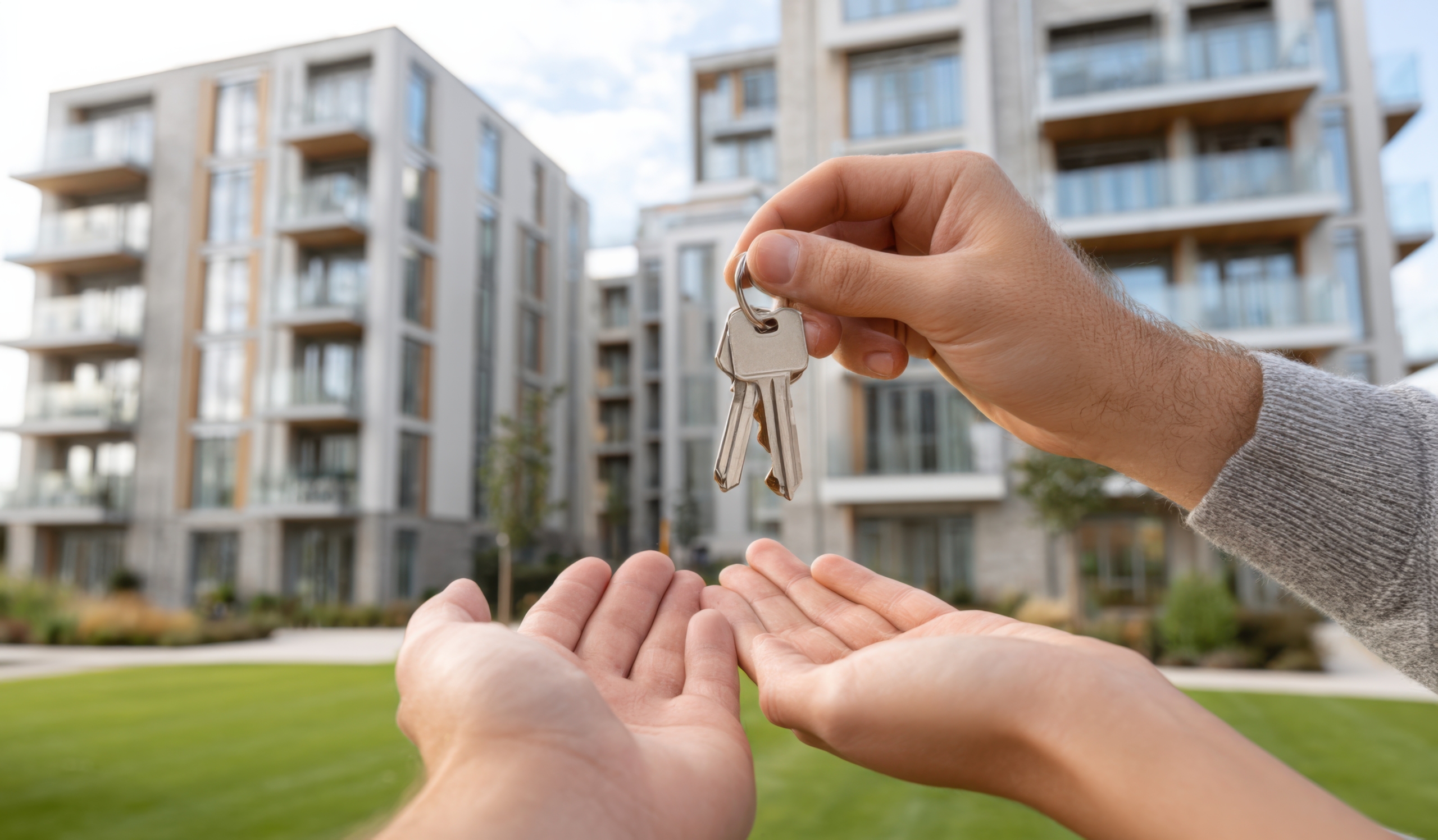 Handing over house keys to a buyer in front of a modern apartment building in Ludhiana